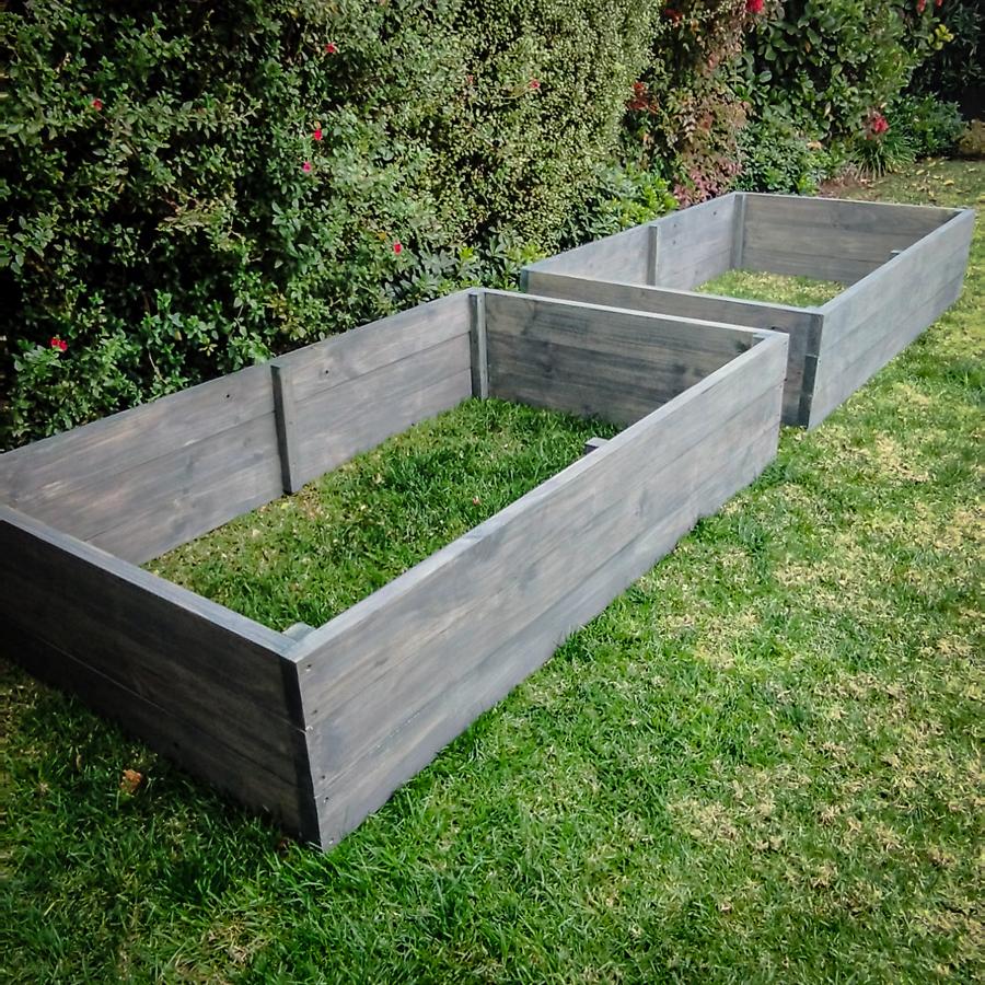 Dos camas de cultivo de madera sobre pasto